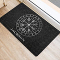 Black Viking entryway mat placed beside a door on light wood flooring