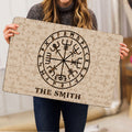 Person holding a Viking rune doormat featuring a central compass symbol and patterned Norse artwork