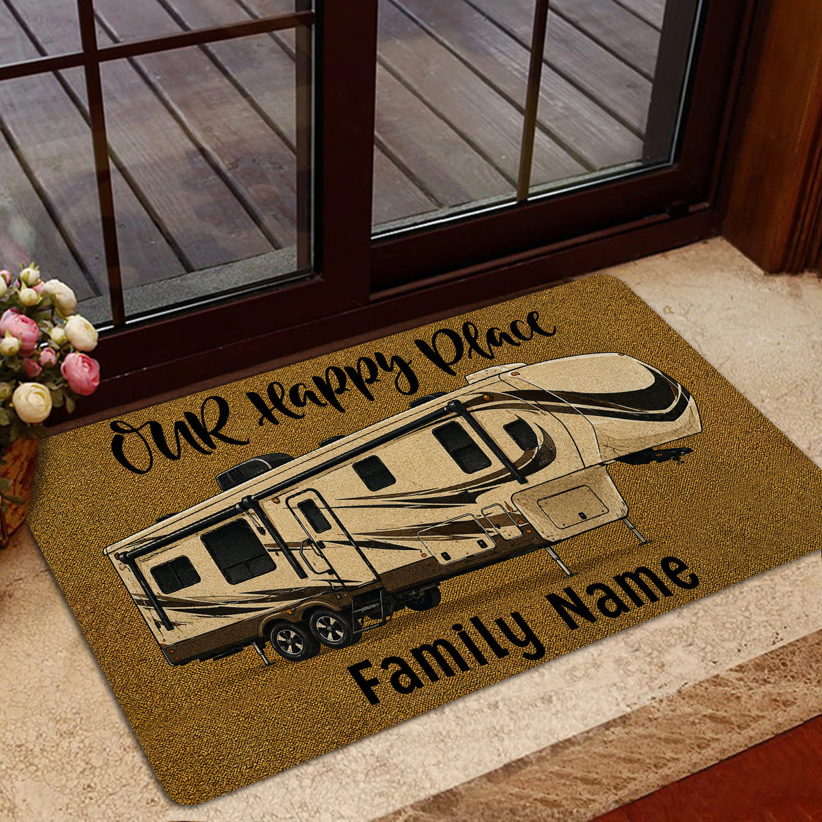 Golden camping door mat with a travel trailer design placed by a glass entry door