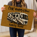 Person holding a gold camping doormat featuring an RV illustration and welcoming artwork