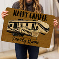 Person holding a golden camping doormat featuring a detailed recreational camper illustration