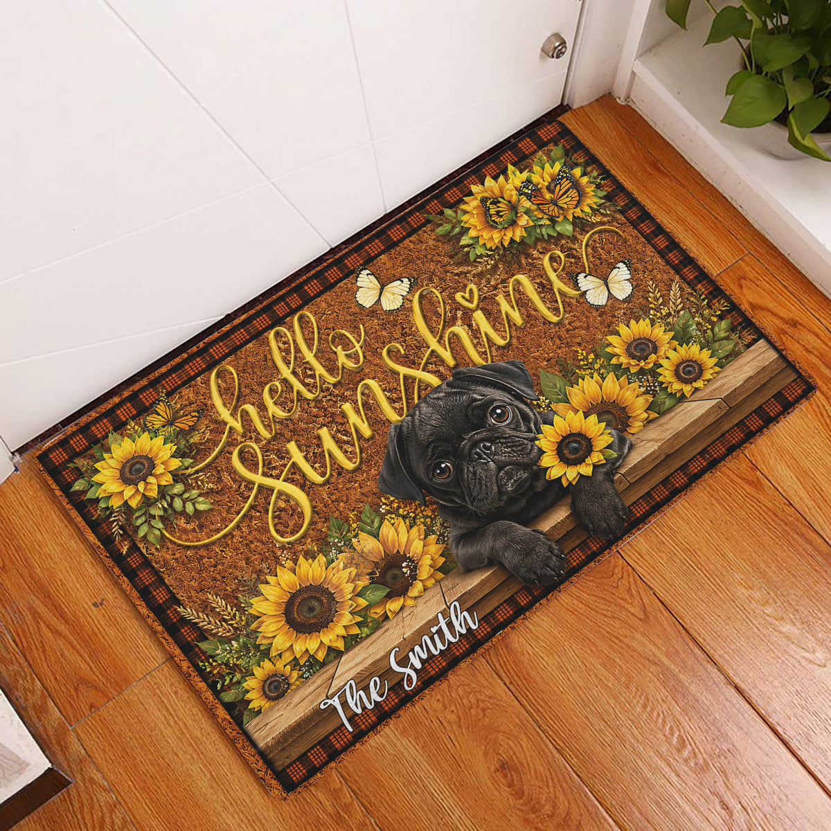 Pug and sunflower doormat displayed in a bright indoor entryway beside a white door