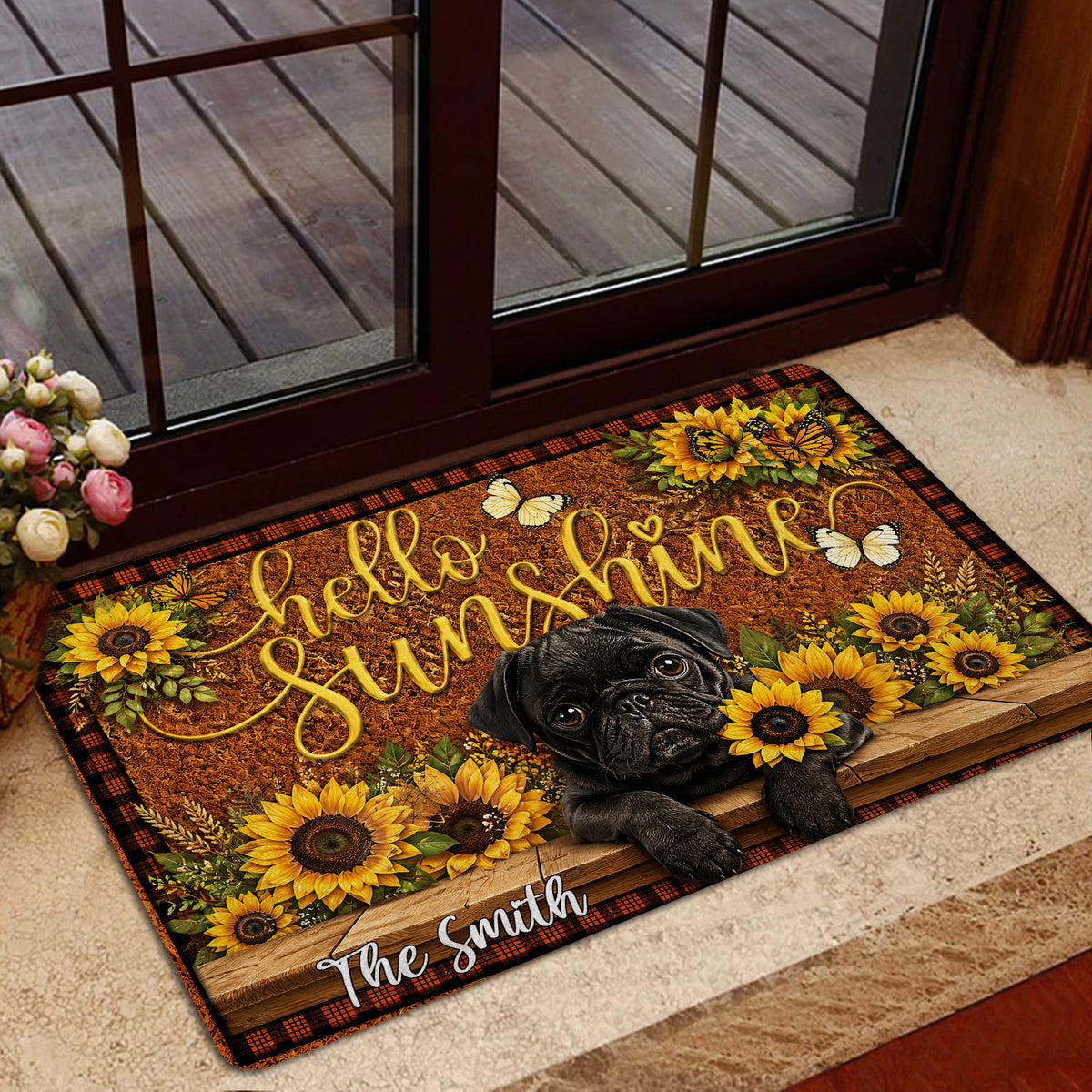 Pug welcome doormat styled at an indoor glass doorway with sunflower and butterfly artwork