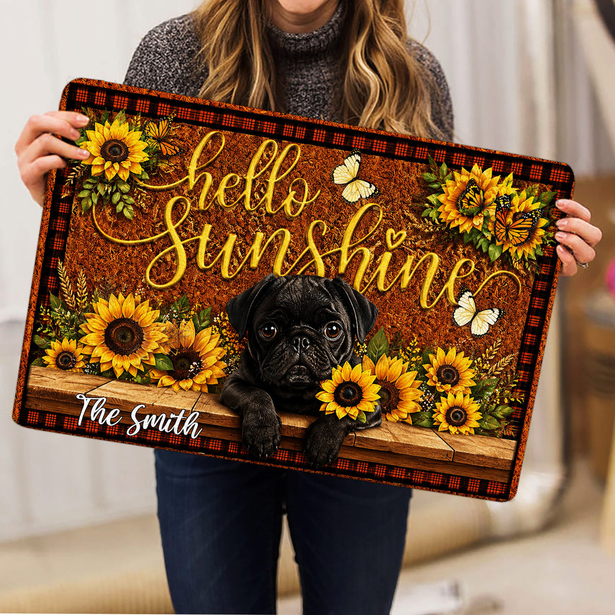 Person holding a colorful pug doormat featuring sunflowers, butterflies, and a warm welcome design