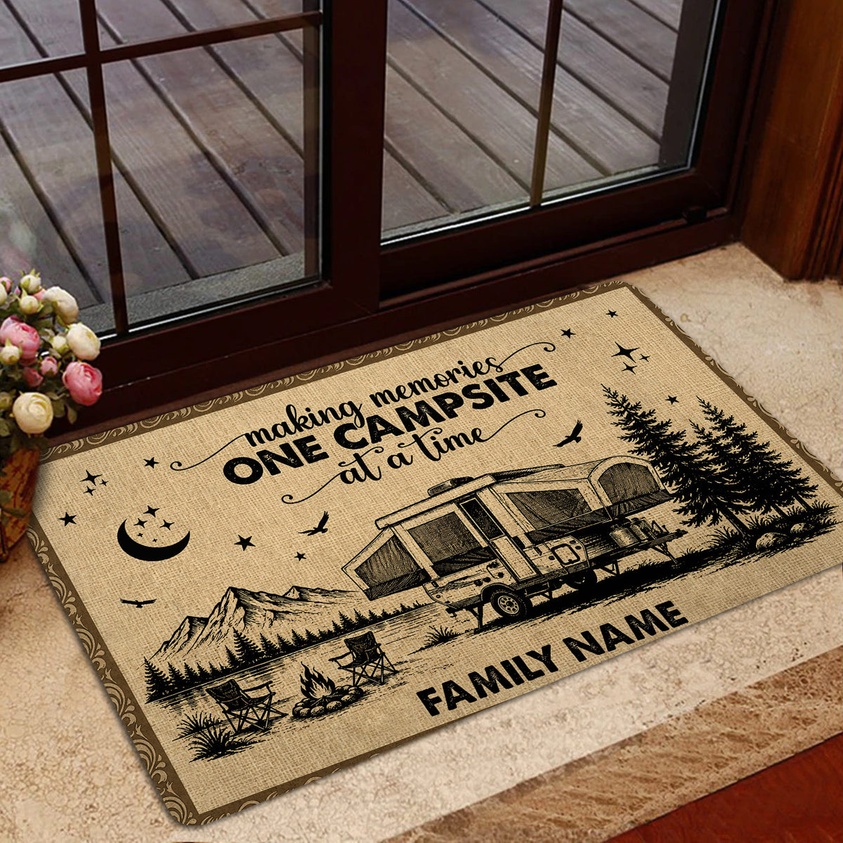 Camping-themed entryway mat displayed by a glass door with RV, mountain, pine tree, and campfire illustration
