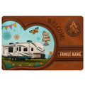 Camping doormat featuring a travel trailer, campfire emblem, butterfly, flowers, and rustic welcome artwork