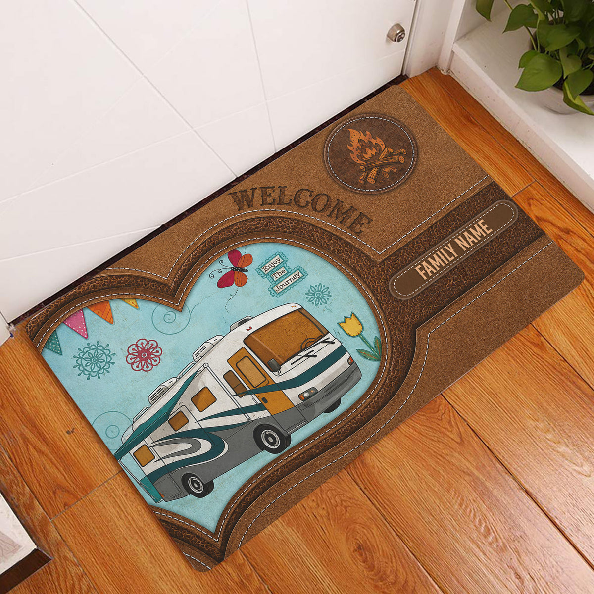 Camping entryway mat displayed by a front door on hardwood flooring with a motorhome and campfire design