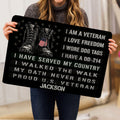 Person holding a black veteran doormat featuring military boots, dog tags, stars, and service-inspired artwork
