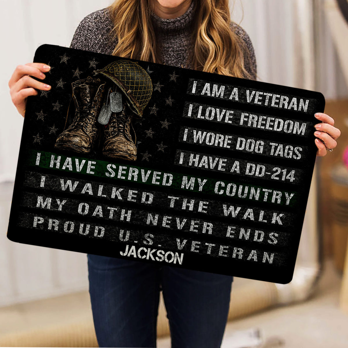 Person holding a veteran doormat featuring military boots, helmet, dog tags, stars, and a patriotic service tribute