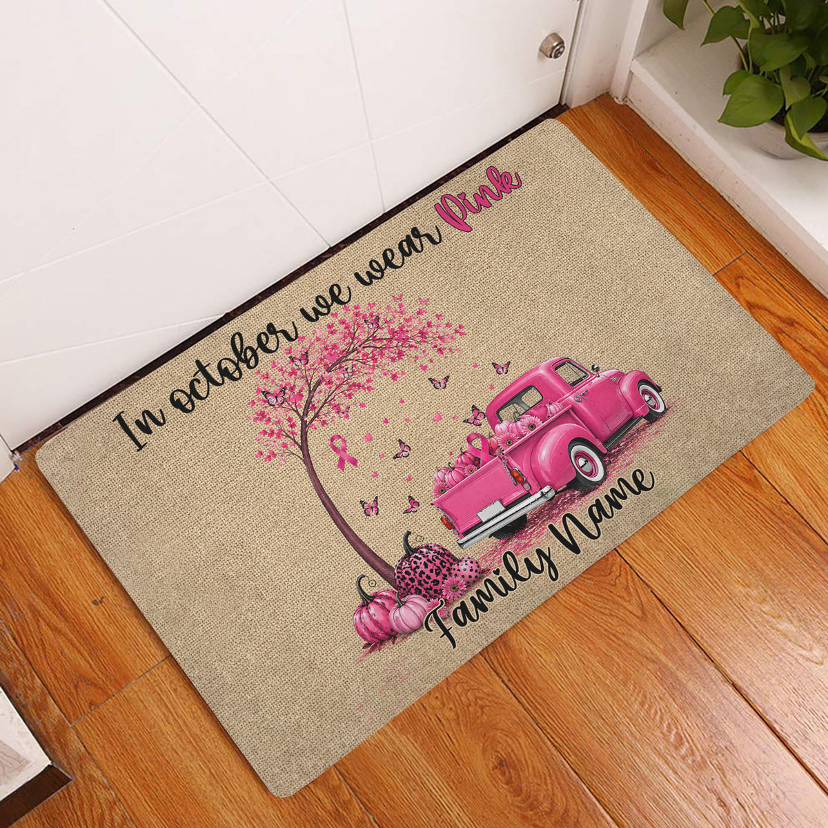 Pink ribbon breast cancer awareness doormat displayed inside a home entryway on a wood floor
