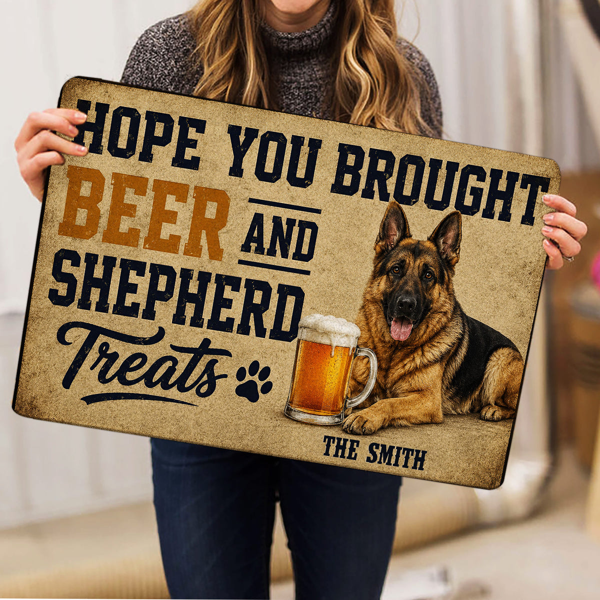 Person holding a German Shepherd doormat featuring a beer mug, paw print, and bold vintage lettering