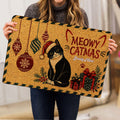 Person holding a Christmas tuxedo cat doormat featuring ornaments and wrapped gifts