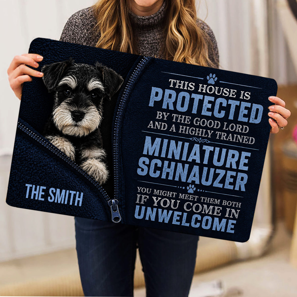 Miniature Schnauzer doormat lifestyle presentation held indoors, showing the dog portrait and typography