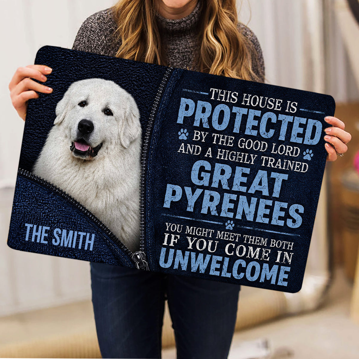 Person holding a Great Pyrenees doormat featuring a white dog portrait and bold navy typography
