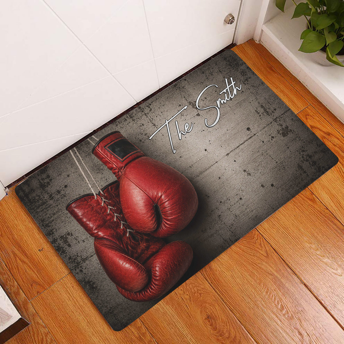Boxing glove entryway mat displayed on a wood floor beside a white door