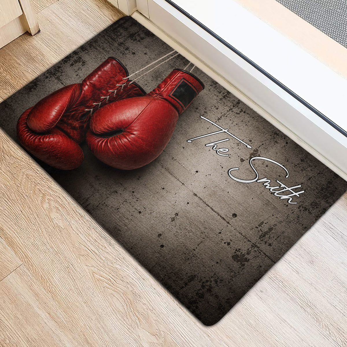 Red boxing gloves printed on a dark doormat placed inside an entryway