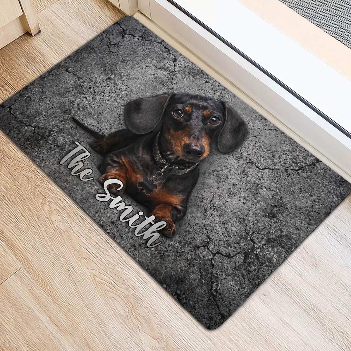 Black and tan dachshund door mat placed inside an entryway near a doorway