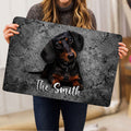 Person holding a dachshund doormat featuring a black and tan dog portrait on a gray background