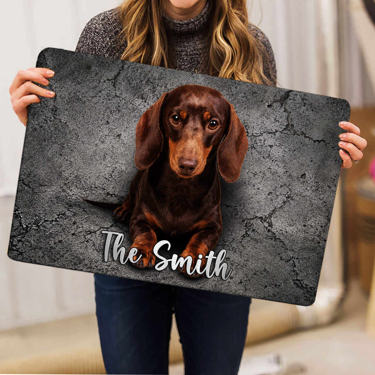 Dachshund doormat held indoors, showing the full dog portrait and gray stone artwork