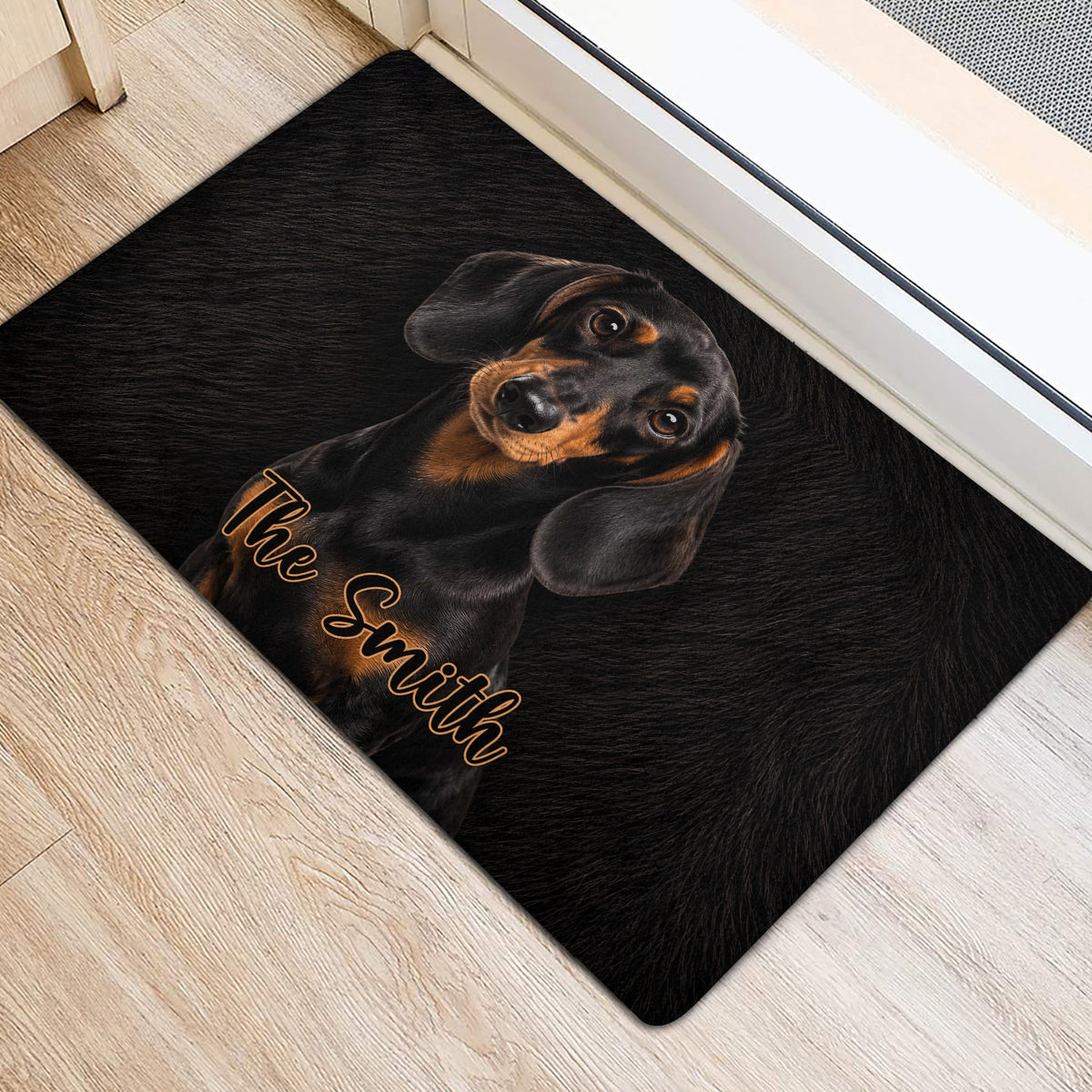 Black dachshund door mat positioned beside an interior doorway on light wood flooring