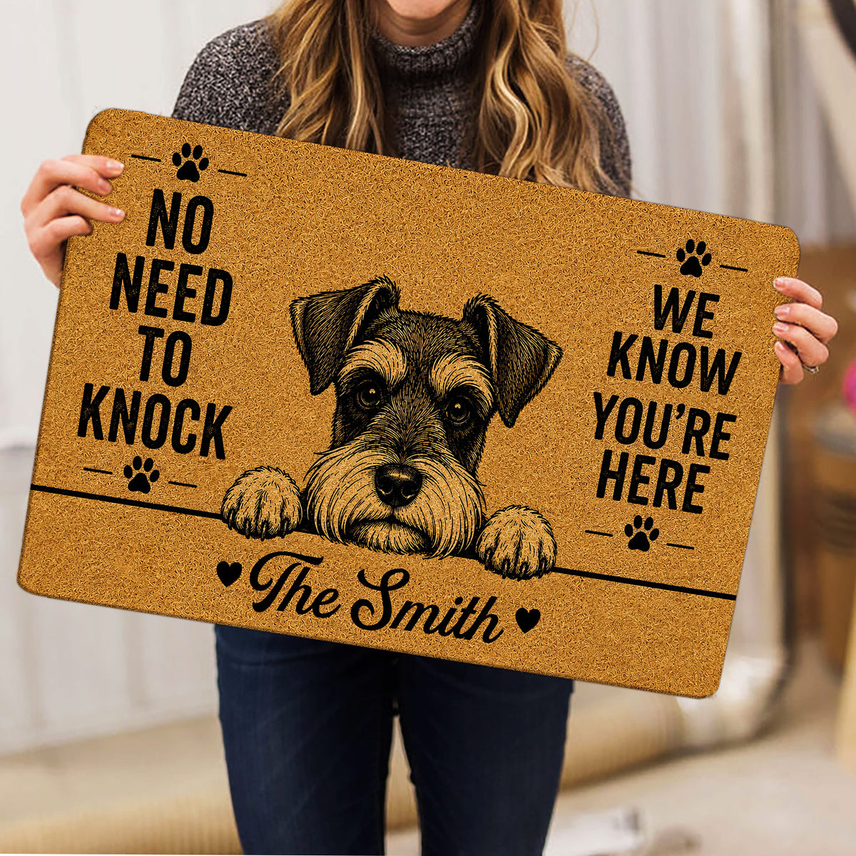Person holding a tan Miniature Schnauzer doormat featuring a dog portrait, paw prints and bold lettering