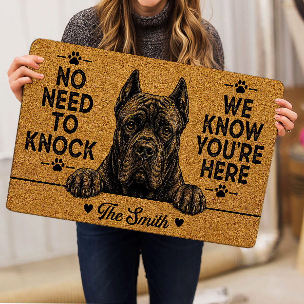 Cane Corso doormat held indoors, featuring a large black illustrated dog portrait and paw-print accents