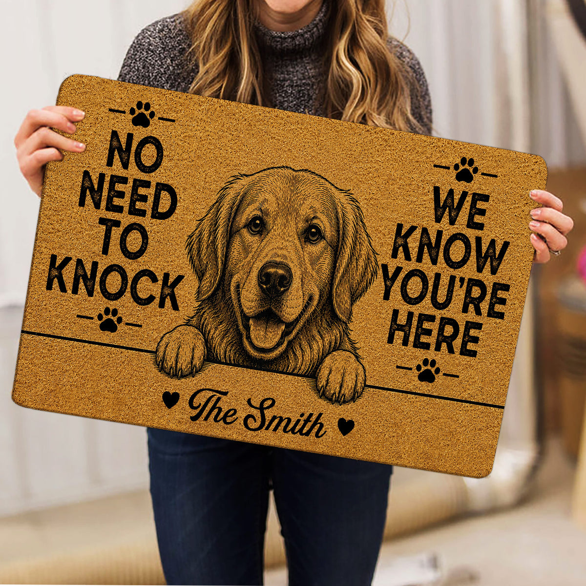 Person holding a Golden Retriever doormat featuring a friendly dog portrait, paw prints, and bold lettering