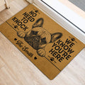 French Bulldog entryway mat with bold black lettering and paw prints displayed beside a light-colored door