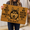 Person holding a tan husky doormat featuring paw prints and a humorous greeting