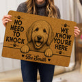 Goldendoodle doormat held indoors, featuring a detailed dog illustration, paw prints and warm tan decor