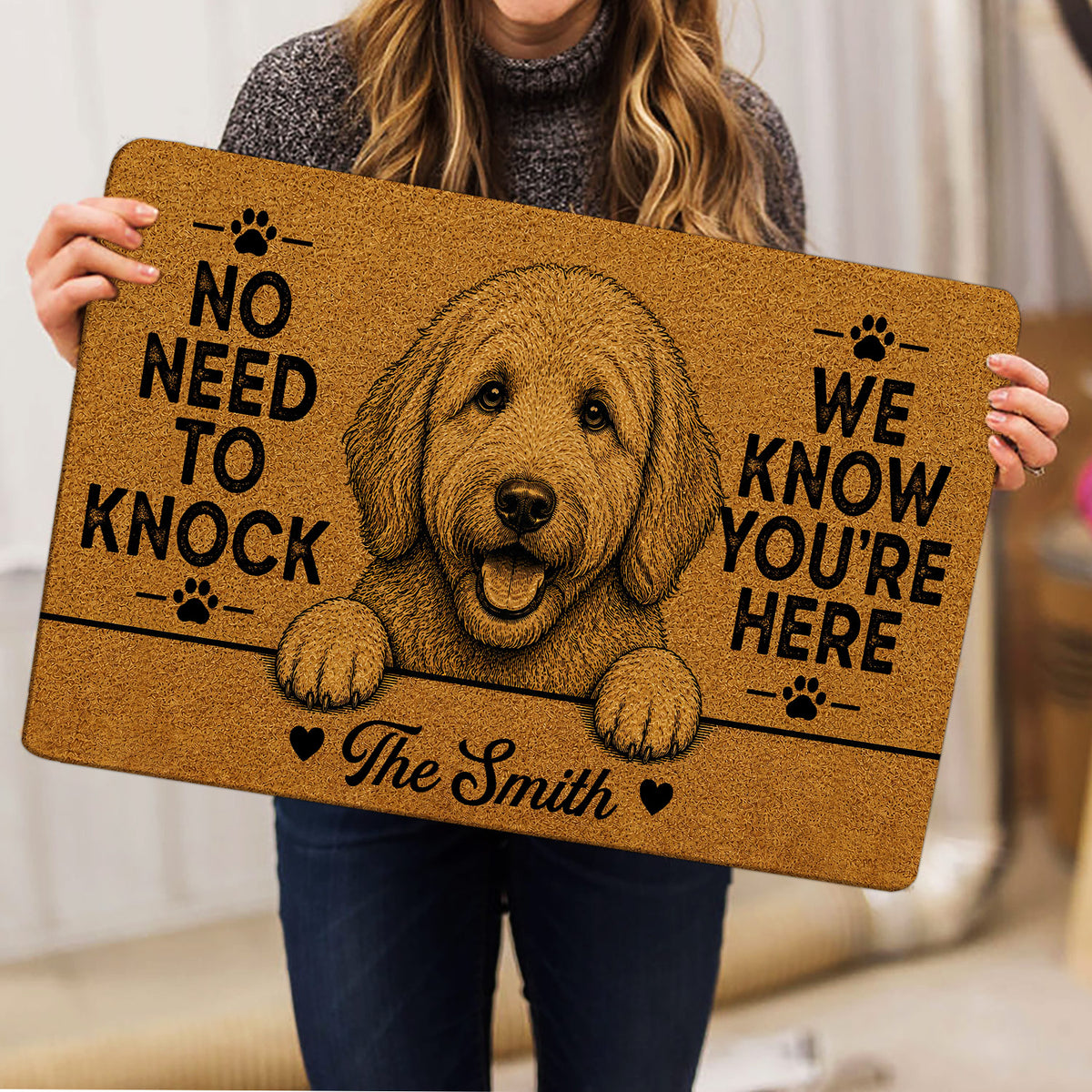 Goldendoodle doormat held indoors, featuring a detailed dog illustration, paw prints and warm tan decor