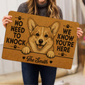 Person holding a golden corgi doormat featuring paw prints, a smiling dog and playful entryway artwork
