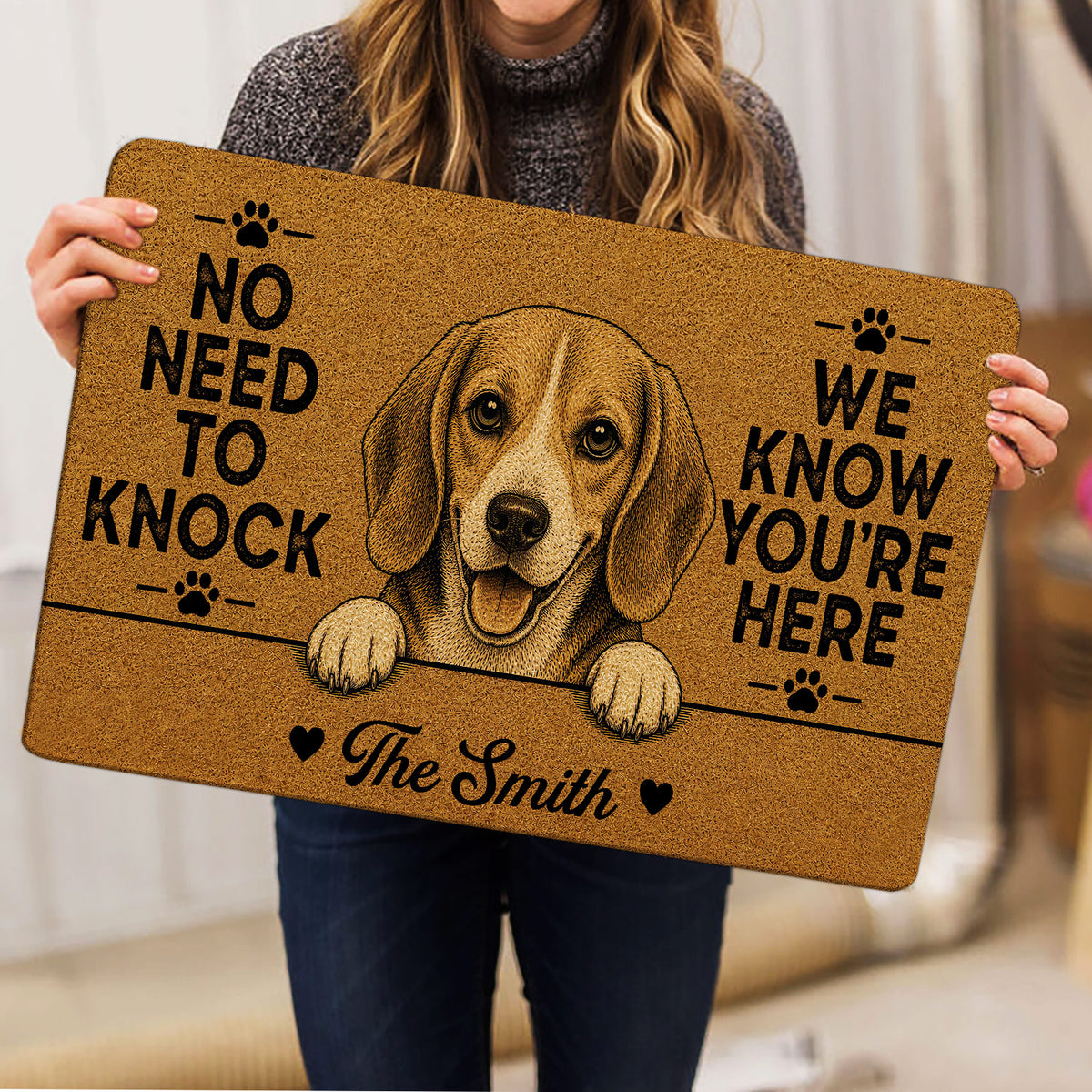 Person holding a brown beagle doormat featuring a cheerful dog portrait and paw prints