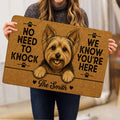 Person holding a tan Yorkie doormat featuring a playful Yorkshire Terrier illustration and paw prints