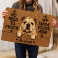 Person holding an English Bulldog doormat featuring a detailed dog portrait, paw prints, and bold black lettering