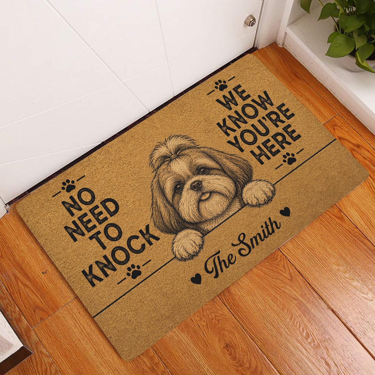 Shih Tzu doormat displayed at an indoor entryway beside a white door and wood flooring