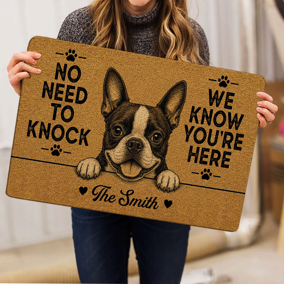 Boston Terrier doormat held indoors, showing the expressive dog illustration, paw prints, and bold black entryway message