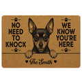Black and tan Miniature Pinscher doormat with paw prints, bold welcome message, and warm brown artwork