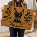 Person holding a Miniature Pinscher doormat with bold paw prints and warm brown artwork