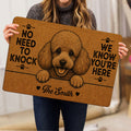 Person holding a brown poodle doormat featuring paw prints, a dog portrait and bold welcome artwork