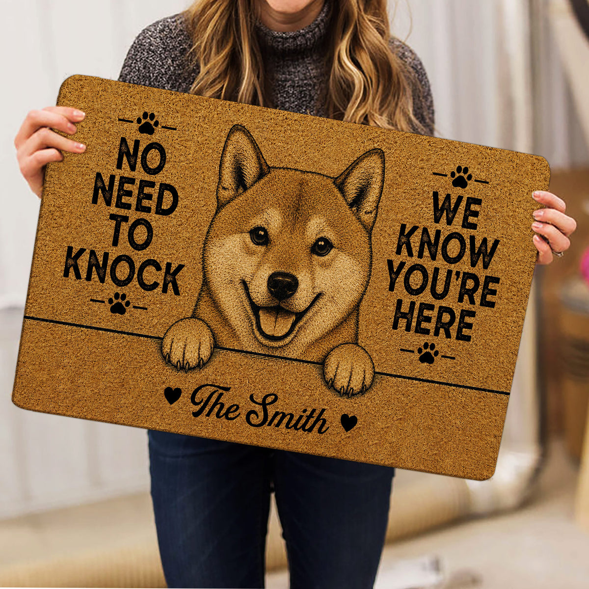Person holding a Shiba Inu doormat featuring a cheerful dog illustration and paw-print design