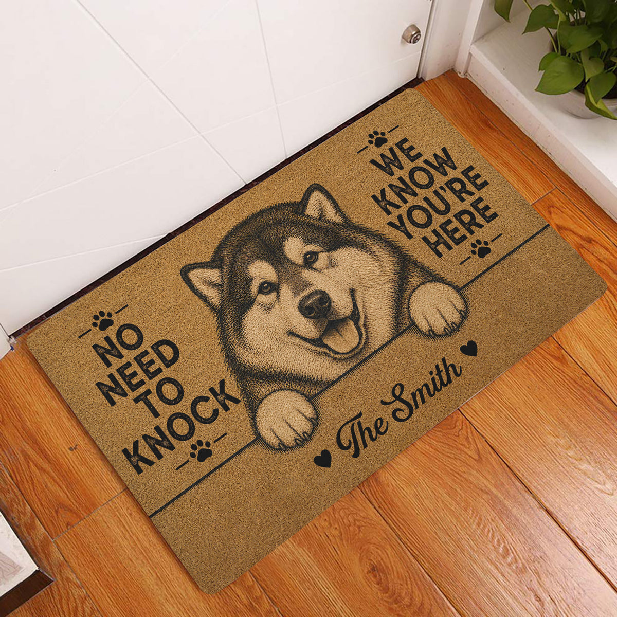 Alaskan Malamute entryway rug displayed beside a white door on a warm wood floor