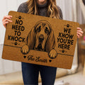 Person holding a tan bloodhound doormat featuring a detailed dog portrait and paw prints