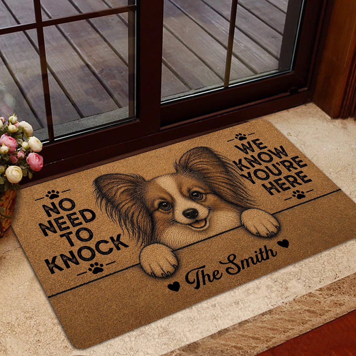 Papillon dog welcome mat styled inside a doorway near a deck and floral arrangement