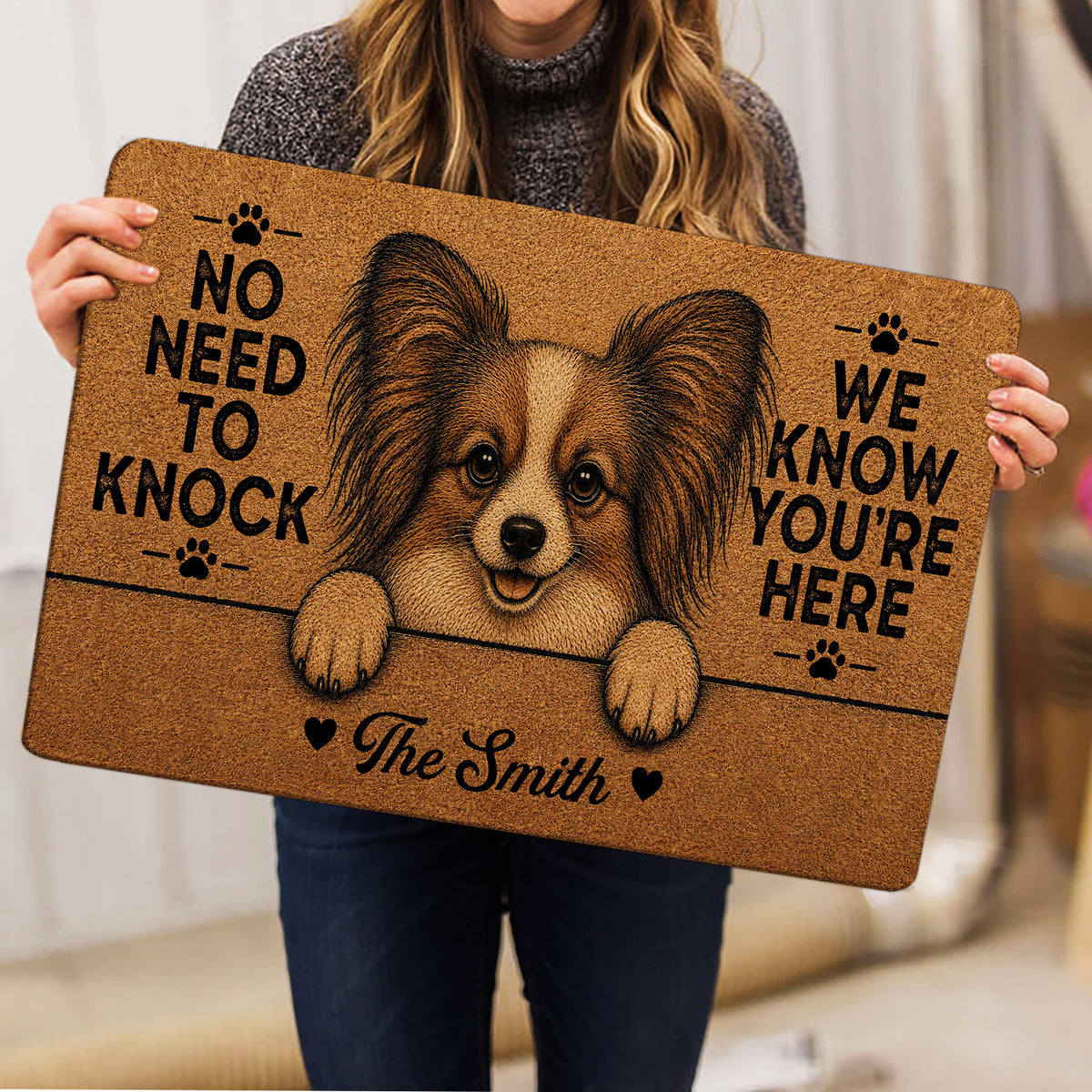 Person holding a Papillon dog doormat featuring a detailed portrait and playful paw print design