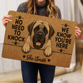 Person holding an English Mastiff doormat featuring tan artwork, paw prints, hearts, and a humorous welcome theme