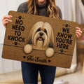 Lifestyle view of a person holding a Lhasa Apso doormat with a detailed dog portrait and paw print design