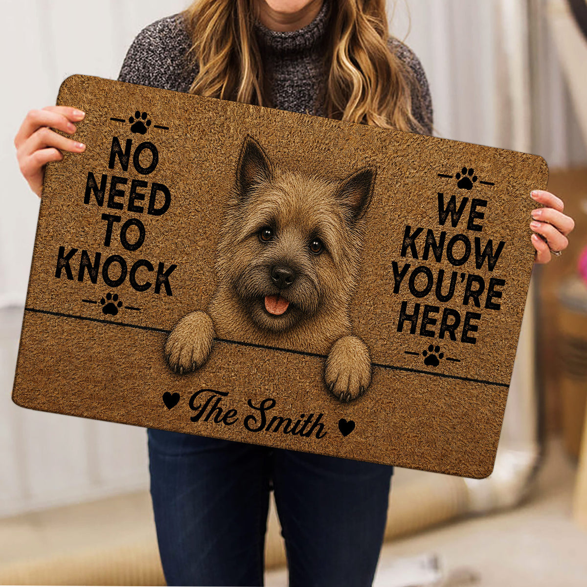 Person holding a Cairn Terrier doormat featuring a shaggy dog portrait and bold black lettering