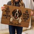 Saint Bernard doormat held indoors, showing the smiling dog portrait, paw prints, and bold lettering