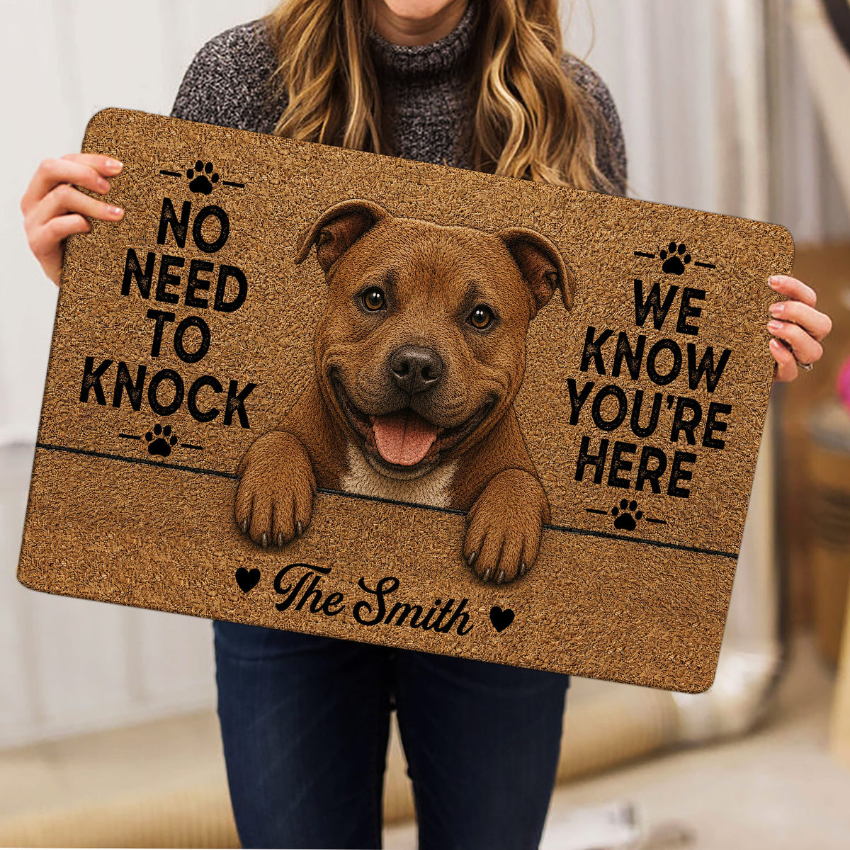 Staffordshire Bull Terrier door mat held indoors, featuring a cheerful dog portrait, paw prints and bold lettering